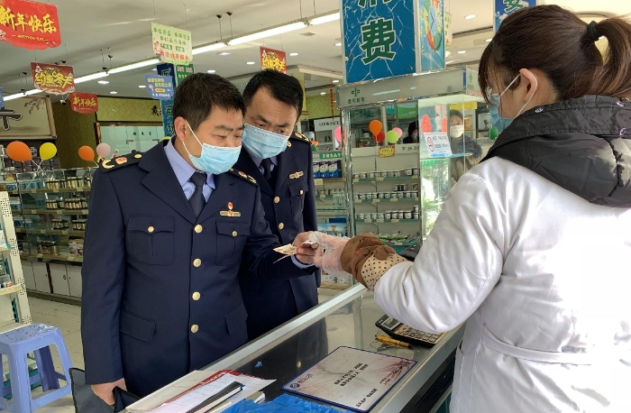 執(zhí)法人員在一家藥店檢查口罩質(zhì)量和進銷價單據(jù)