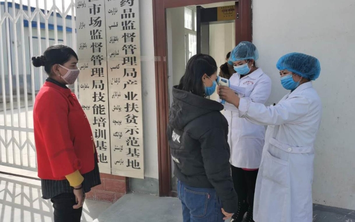 工人在進(jìn)入工廠前測(cè)量體溫并登記。（駐村工作隊(duì)供圖）