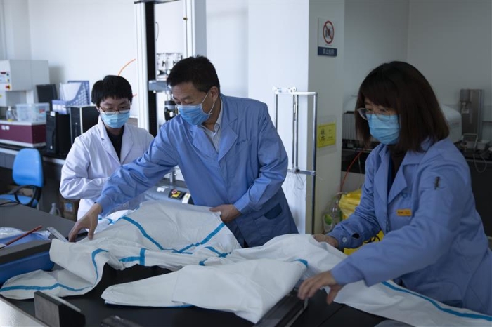 圖為趙玉杰（中）檢查醫(yī)用防護(hù)服應(yīng)急檢測工作。