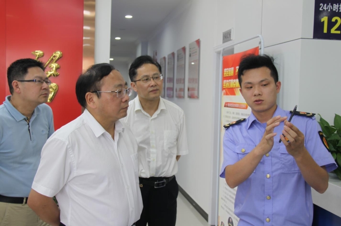 上官新晨（左二）在鷹潭市局東湖分局觀看基層執(zhí)法人員演示如何運用智慧市場監(jiān)管網格化管理平臺開展監(jiān)督檢查工作等情況。