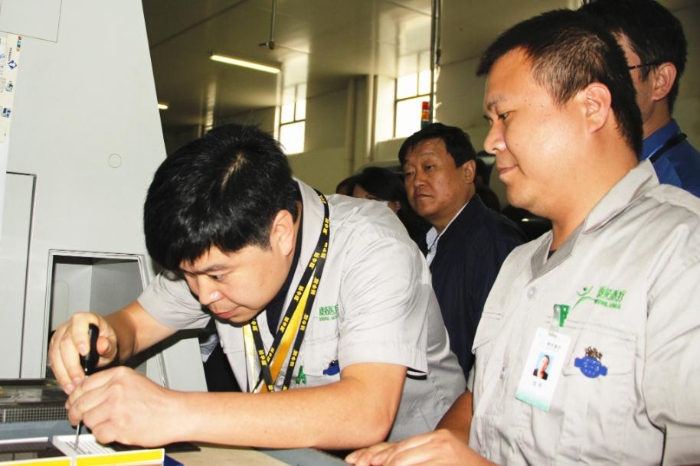 工作人員在生產(chǎn)車間現(xiàn)場向大家演示產(chǎn)品和工具的精準(zhǔn)配合性能（賀一辰 攝）