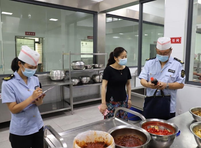 圖為執(zhí)法人員在檢查學(xué)校食堂加工制作情況。