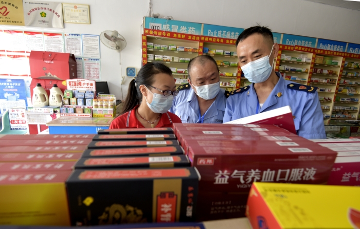 圖為執(zhí)法人員在一家藥店檢查中成藥質(zhì)量。