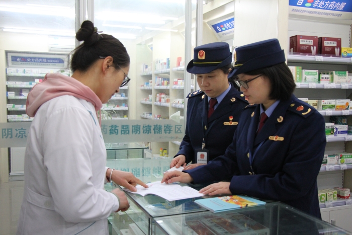 圖為執(zhí)法人員在佰藥之家大藥房發(fā)放安全用藥科普手冊。