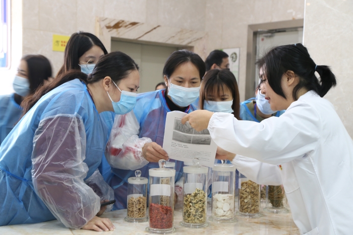 圖為工作人員為市民代表講解中藥材真?zhèn)舞b別知識。