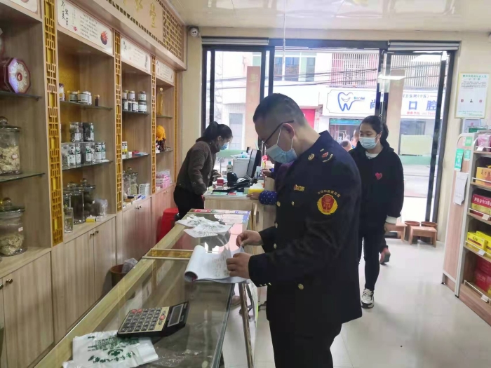 圖為執(zhí)法人員在一家藥店查看登記臺賬。