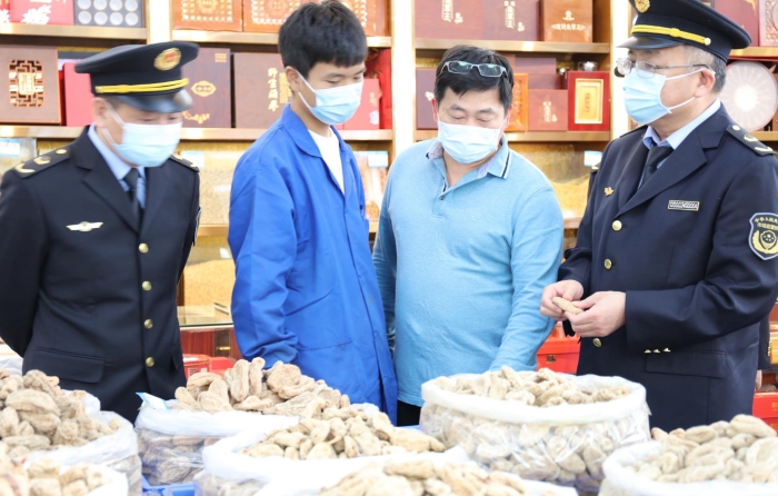 秦繼紅（右一）在中藥材市場門店查看。（喻燦華 攝）