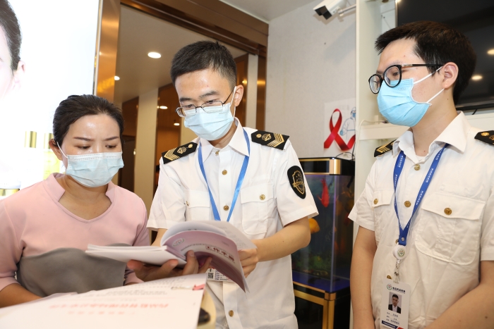 圖為抽檢人員向經(jīng)營者宣貫化妝品監(jiān)管法規(guī)文件。