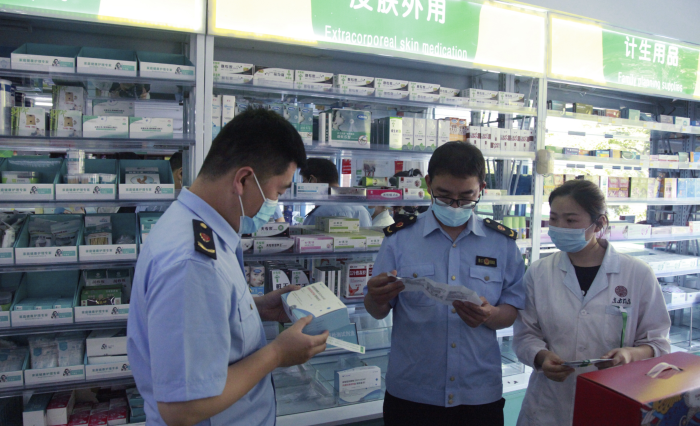 圖為青州市市場監(jiān)管局執(zhí)法人員在一家藥店檢查抗原檢測試劑盒質(zhì)量。