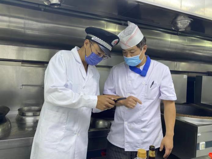 圖為海淀區(qū)市場(chǎng)監(jiān)管局執(zhí)法人員檢查學(xué)校食堂食品安全。